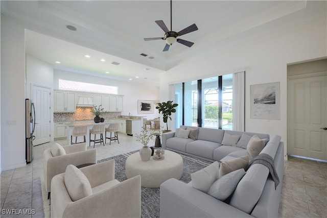 living room with ceiling fan and a high ceiling