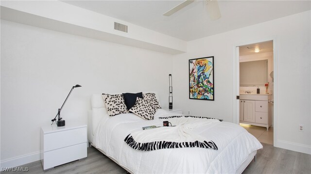 bedroom with ceiling fan, ensuite bath, and wood-type flooring