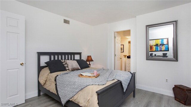 bedroom with light hardwood / wood-style flooring and connected bathroom