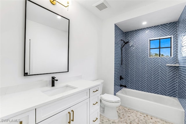 full bathroom featuring vanity, tiled shower / bath, and toilet