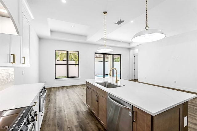 kitchen with white cabinetry, dark wood-type flooring, stainless steel appliances, decorative light fixtures, and sink