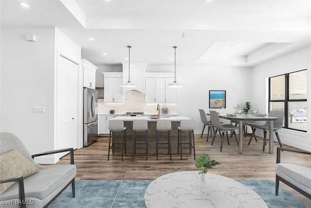 interior space with hanging light fixtures, stainless steel fridge, dark wood-type flooring, and an island with sink