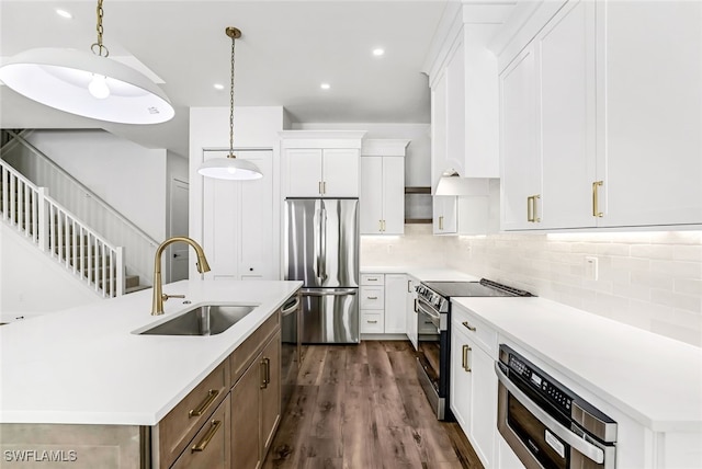 kitchen featuring white cabinetry, sink, stainless steel appliances, and decorative light fixtures