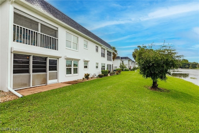 back of property featuring a lawn and a water view