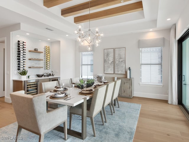 dining area with a notable chandelier, beamed ceiling, beverage cooler, and light hardwood / wood-style floors