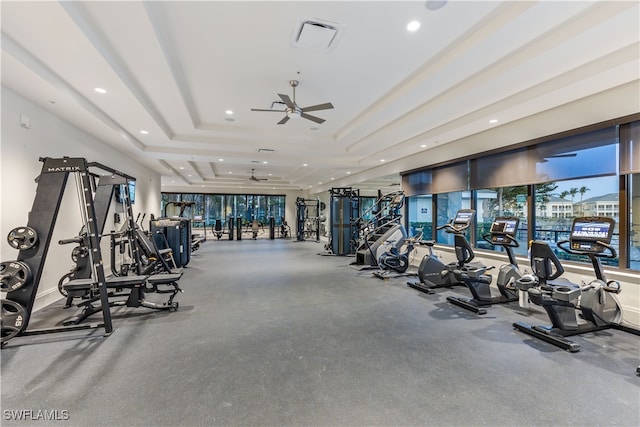 workout area featuring a tray ceiling and ceiling fan