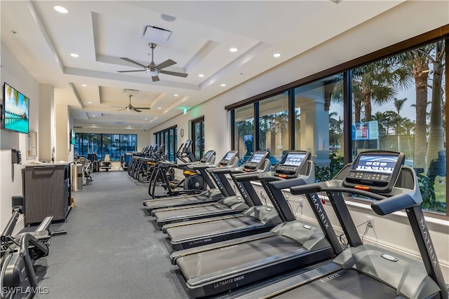 gym featuring a tray ceiling and ceiling fan