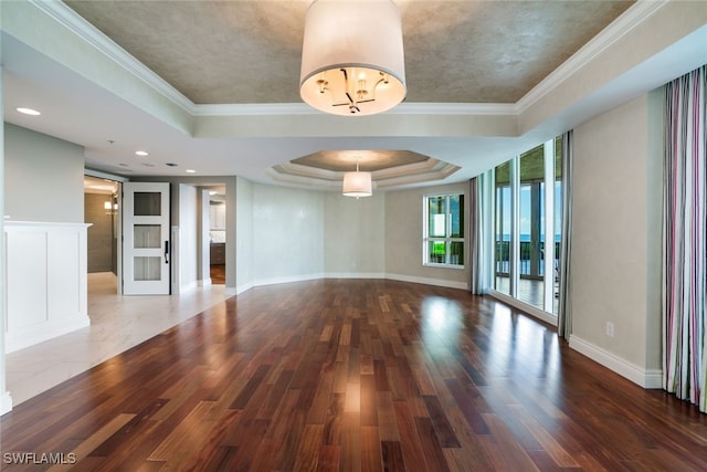 unfurnished living room with a tray ceiling, dark hardwood / wood-style floors, and crown molding