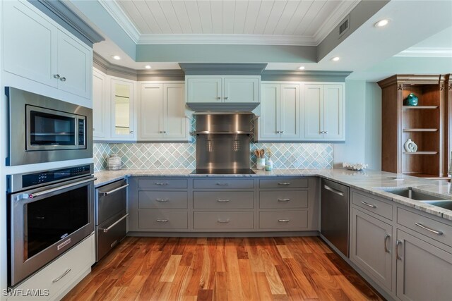 kitchen with ornamental molding, stainless steel appliances, kitchen peninsula, and light wood-type flooring