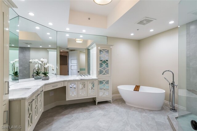 bathroom with vanity, a freestanding tub, recessed lighting, and visible vents