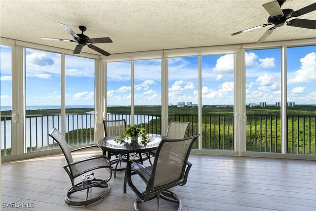 sunroom with a water view and ceiling fan