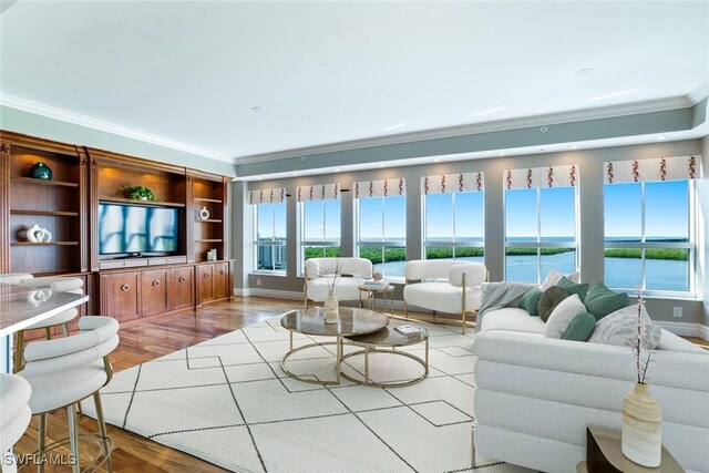 living room with light wood-type flooring, crown molding, and a water view