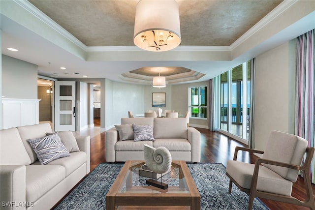 living area with a raised ceiling, wood finished floors, and ornamental molding