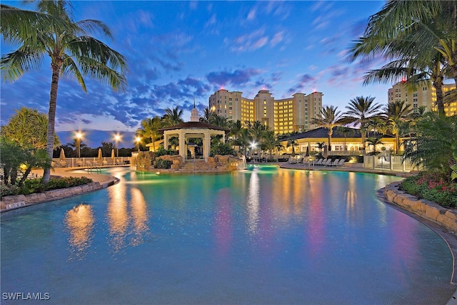 pool at dusk with a gazebo and a patio