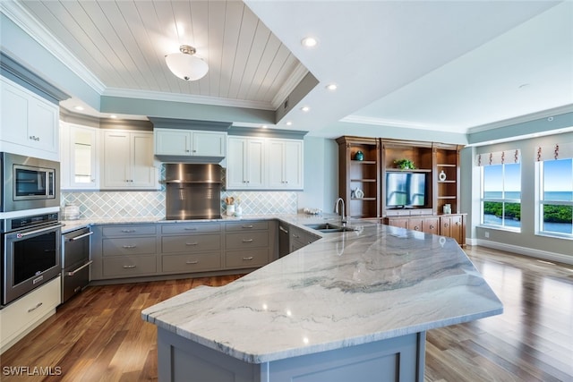 295 Grande Way Unit 1004, Naples, FL 34110 - kitchen with appliances with stainless steel finishes, ornamental molding, a peninsula, wood finished floors, and gray cabinetry