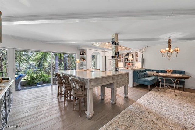 dining area featuring an inviting chandelier, wood-type flooring, and beam ceiling