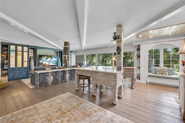 interior space featuring ornamental molding, lofted ceiling with beams, and hardwood / wood-style floors