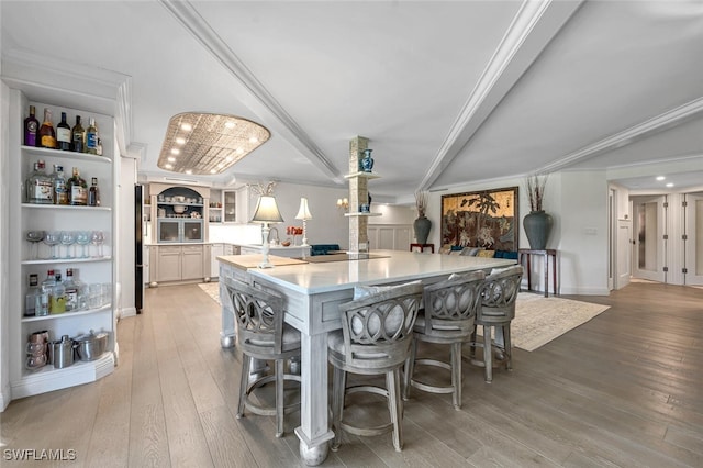 kitchen with a large island, a kitchen bar, black electric stovetop, ornamental molding, and hardwood / wood-style floors