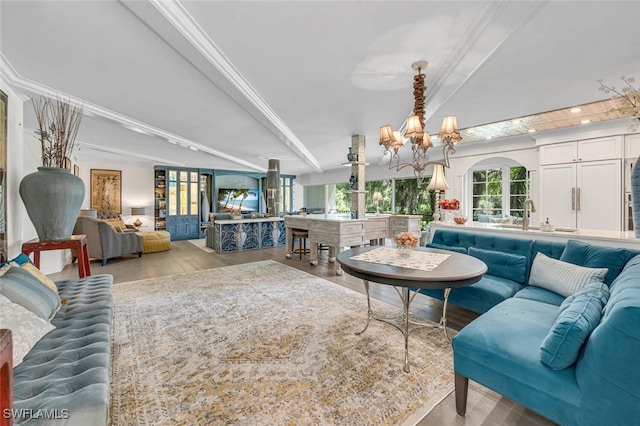 living room with sink, a chandelier, light hardwood / wood-style floors, and crown molding