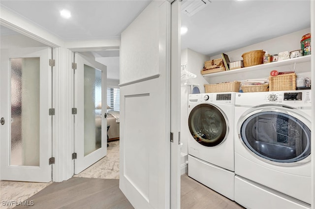 clothes washing area featuring light wood-type flooring and independent washer and dryer