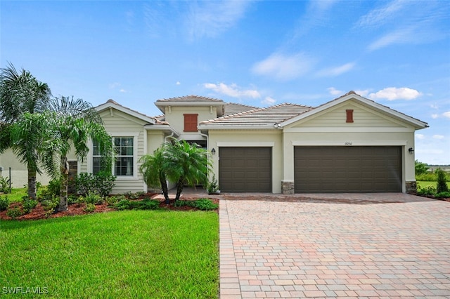 view of front facade with a garage, a front lawn, decorative driveway, and a tiled roof