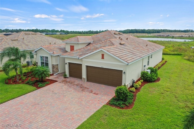 view of front facade featuring decorative driveway, stucco siding, a garage, a tiled roof, and a front lawn