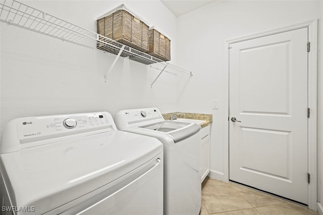 laundry room with cabinet space, light tile patterned flooring, and washing machine and clothes dryer