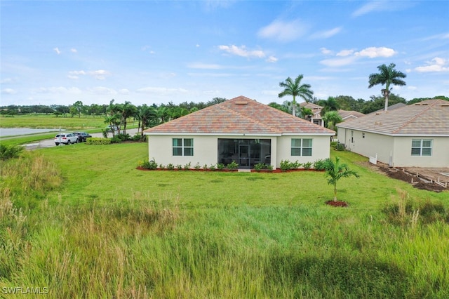 rear view of house featuring a lawn and stucco siding