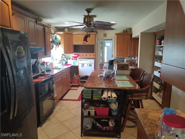 kitchen featuring ceiling fan, light tile patterned floors, light stone countertops, and black appliances