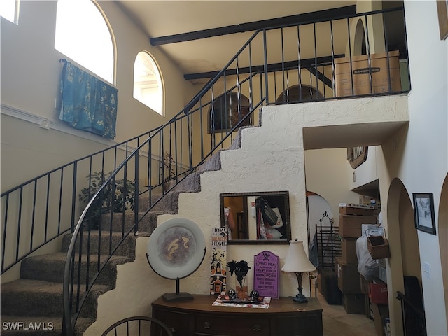 stairway featuring a towering ceiling