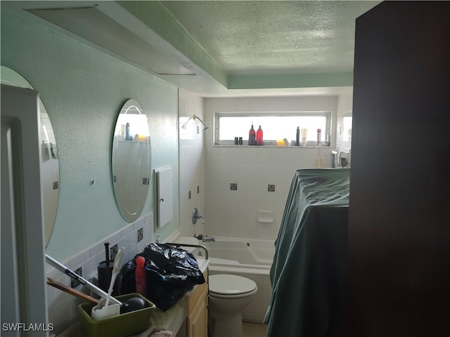 full bathroom with tiled shower / bath combo, toilet, vanity, and a textured ceiling