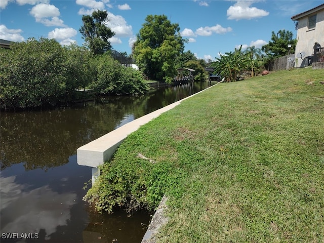 view of dock with a yard and a water view