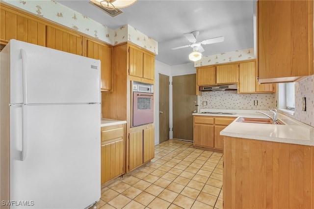 kitchen featuring sink, range hood, white appliances, light tile patterned floors, and ceiling fan