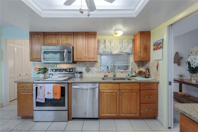 kitchen featuring stainless steel appliances, a tray ceiling, sink, and tasteful backsplash