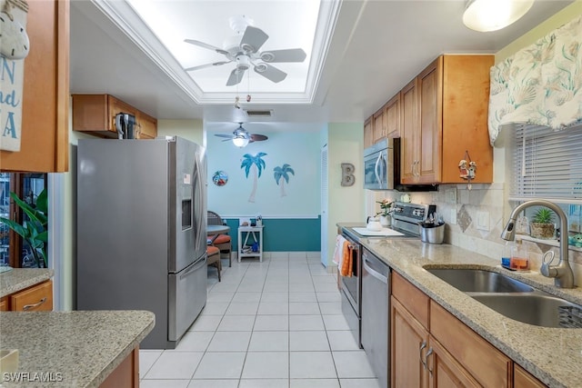 kitchen featuring light tile patterned flooring, sink, appliances with stainless steel finishes, a skylight, and a tray ceiling