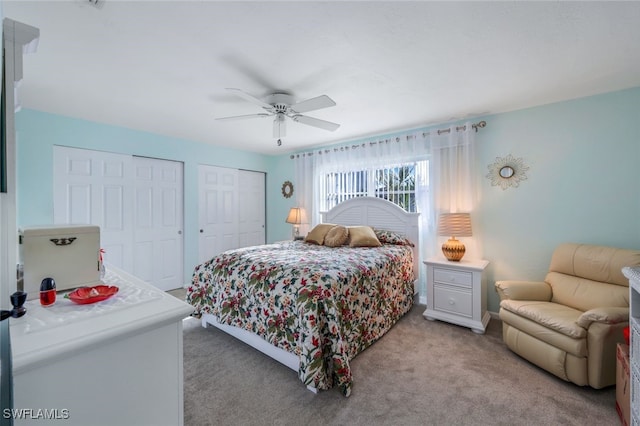 carpeted bedroom featuring multiple closets and ceiling fan