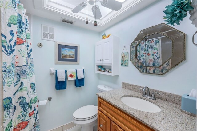 bathroom featuring ceiling fan, vanity, toilet, and a raised ceiling