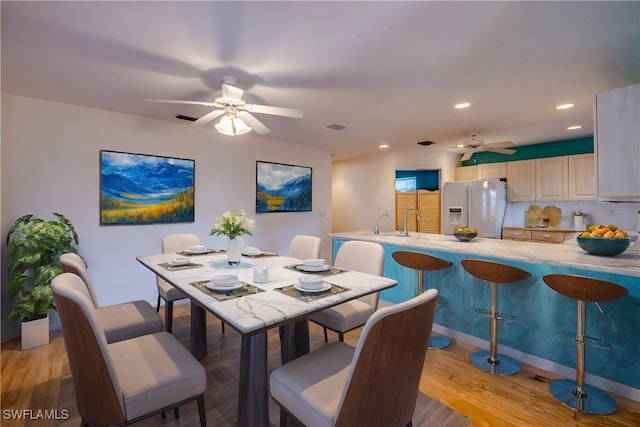 dining room with light hardwood / wood-style floors, ceiling fan, and sink