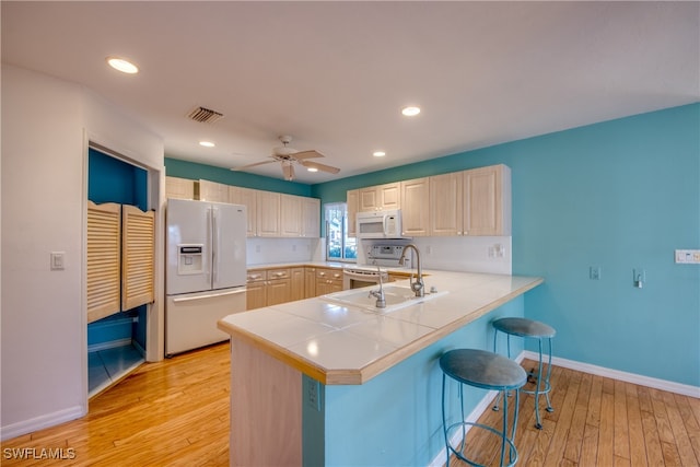 kitchen featuring sink, light hardwood / wood-style flooring, kitchen peninsula, and white appliances