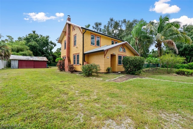 rear view of property featuring a storage shed and a yard