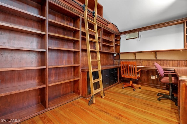 office space featuring wooden walls, built in desk, and light hardwood / wood-style floors