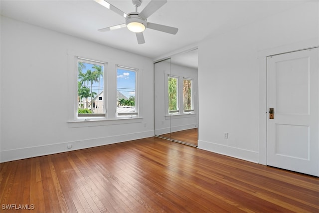 empty room featuring a wealth of natural light, ceiling fan, and hardwood / wood-style flooring