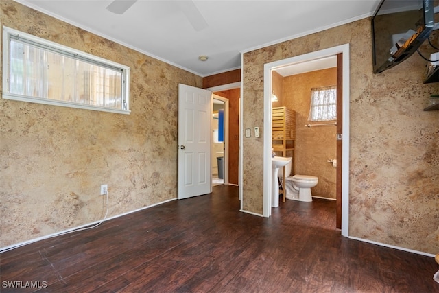 unfurnished bedroom with ceiling fan, ornamental molding, ensuite bathroom, and dark wood-type flooring