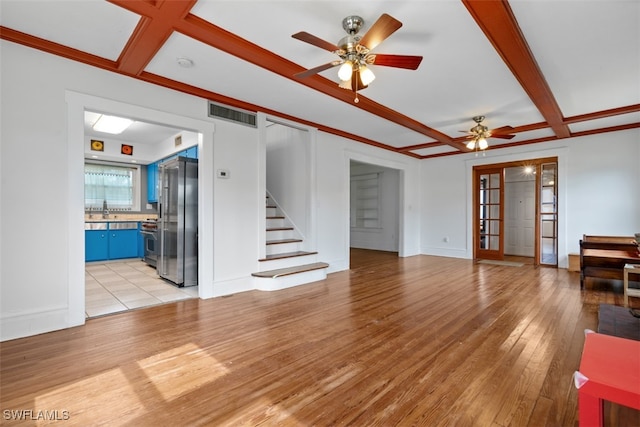 unfurnished living room featuring light wood-type flooring, beam ceiling, ceiling fan, french doors, and sink