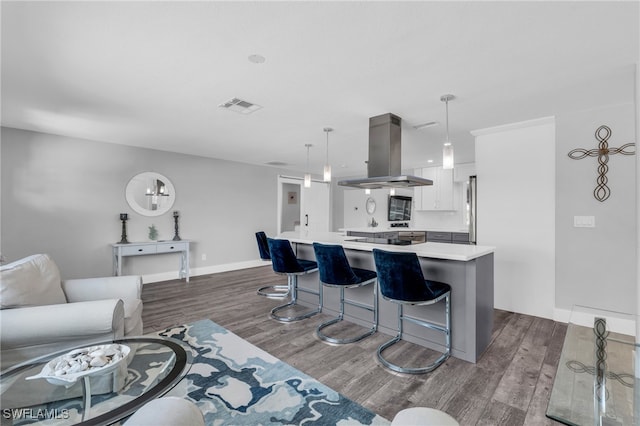 kitchen featuring a kitchen island, white cabinets, dark hardwood / wood-style flooring, island range hood, and hanging light fixtures