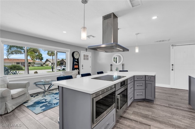 kitchen with island exhaust hood, decorative light fixtures, appliances with stainless steel finishes, and gray cabinets