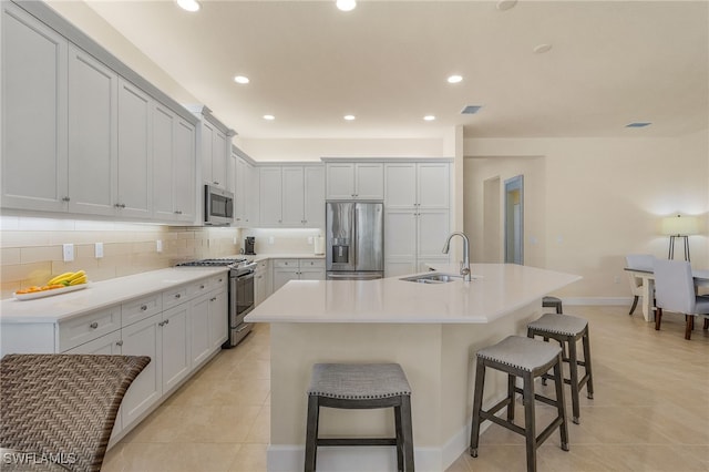 kitchen with a kitchen bar, a kitchen island with sink, appliances with stainless steel finishes, and sink