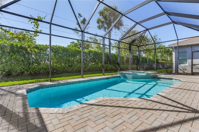 view of pool with glass enclosure, an in ground hot tub, and a patio area