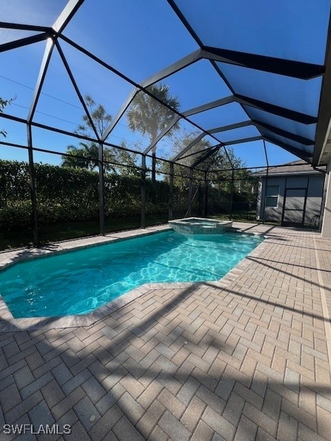 view of pool with a patio, glass enclosure, and an in ground hot tub