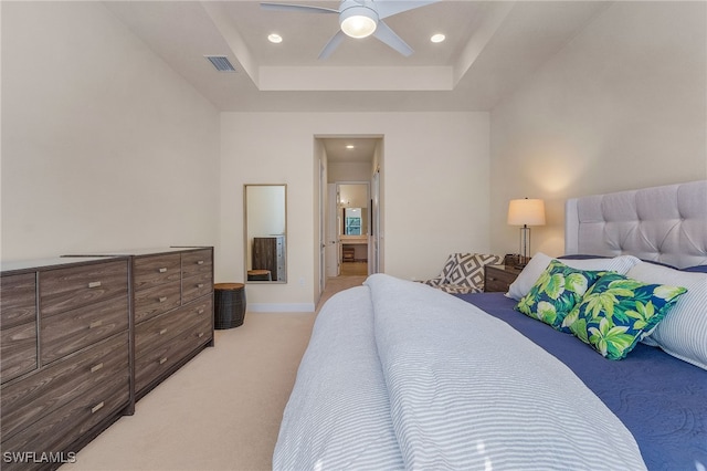 bedroom with ceiling fan, light colored carpet, and a tray ceiling